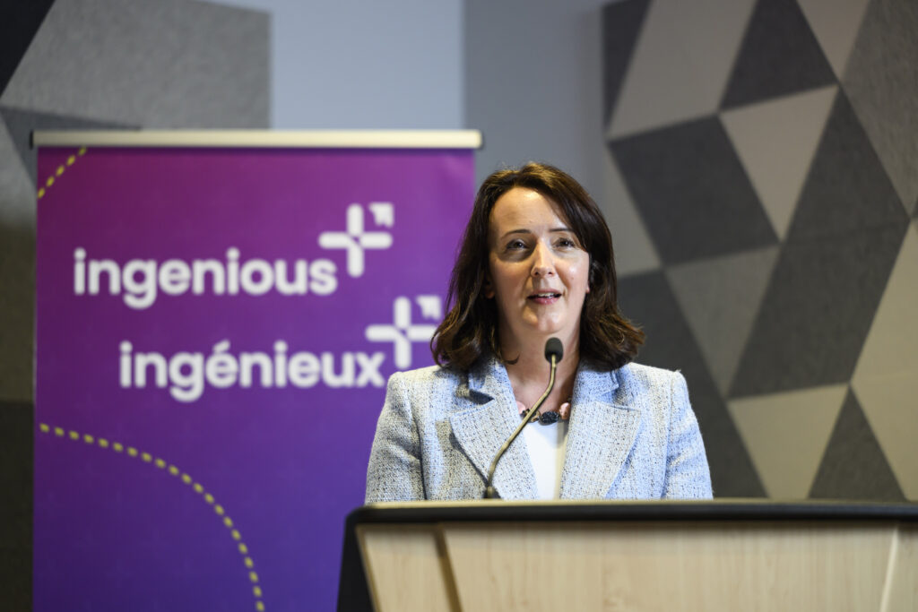 Teresa Marques, President and CEO of Rideau Hall Foundation, speaking at a podium with an Ingenious+ banner behind her