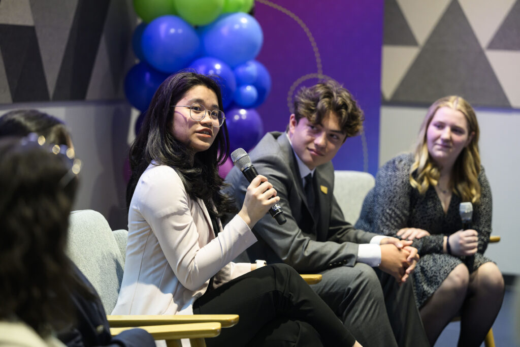 Kendra Nayanka answering a question while Liam Pope-Lau and Natalie Mitchell watch and listen in the background