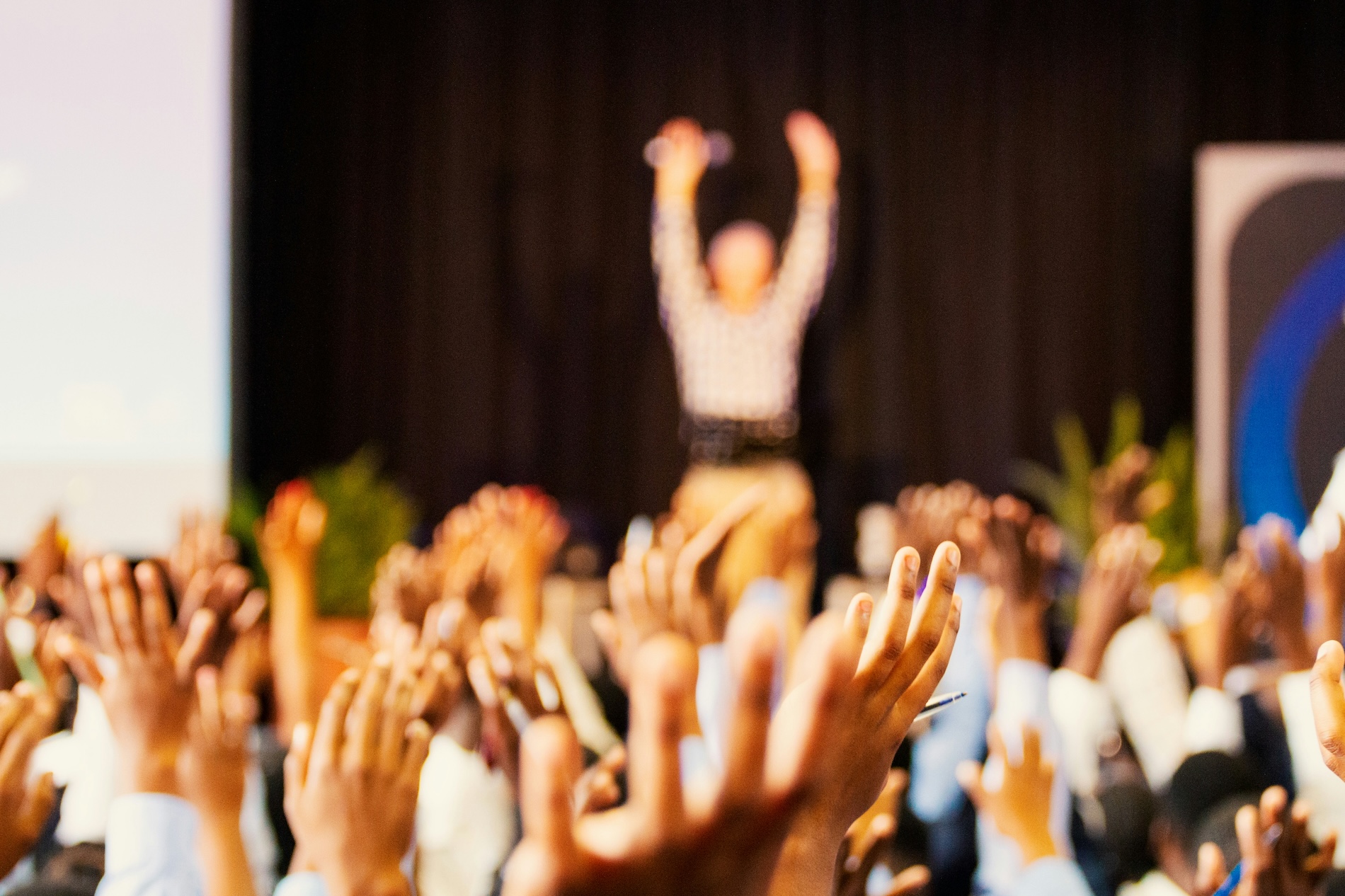 crowd raising hands at speaker in audience